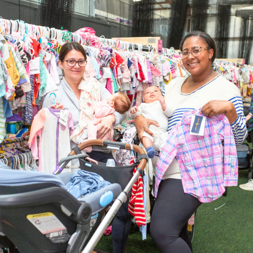 Two friends with infants shop a JBF sale. 